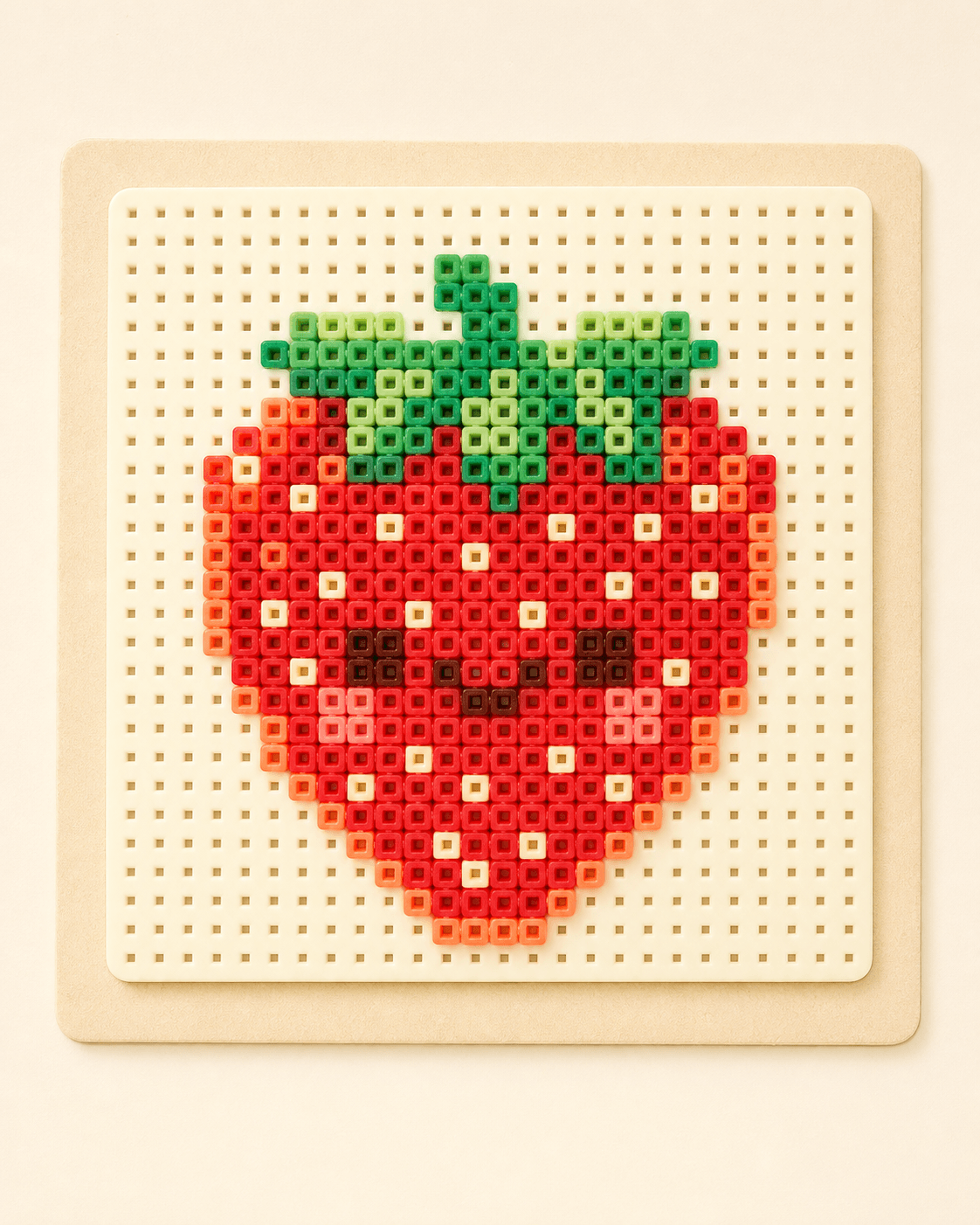 A strawberry fuse-bead pattern on a pegboard